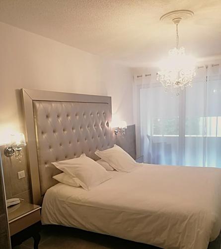 a bedroom with a white bed and a chandelier at Hôtel Les Deux Lions in Riez