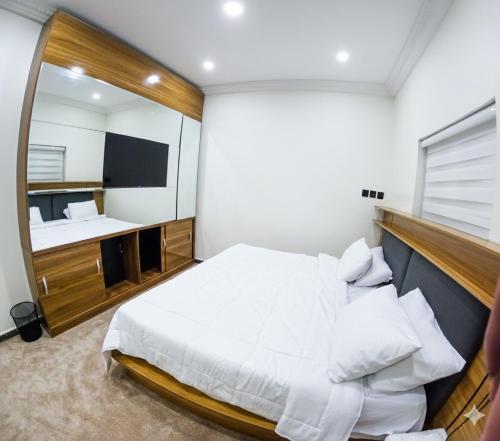 a bedroom with a large white bed and a mirror at DimpleTravelodge in Lagos