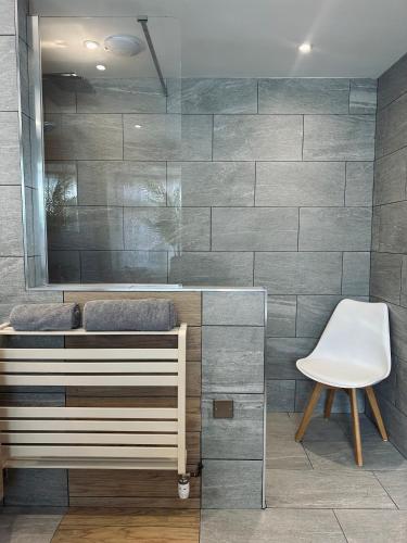 a bathroom with a mirror and a white chair at Botanical Suite Ryde Isle of Wight in Isle of Wight