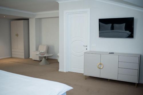 a white bedroom with a bed and a white dresser at Pensiunea Paradis in Râmnicu Vâlcea