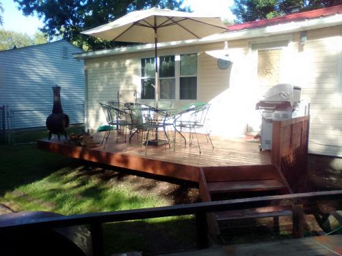 a wooden deck with chairs and an umbrella at Cozy 2 Bedroom Home in Madison