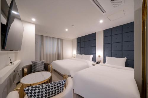 a hotel room with two beds and a table and chairs at 그랜디스 호텔 문현 in Busan