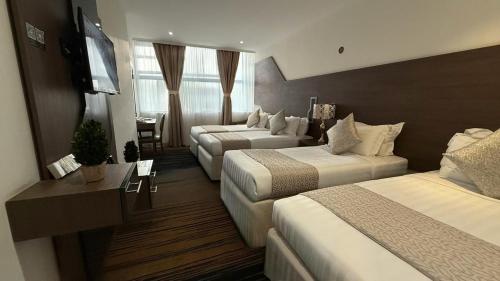 a hotel room with three beds and a television at Lamar Ajyad First Hotel Tower A in Makkah