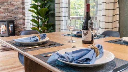 a wooden table with a bottle of wine and glasses at Wooded Nest, Cozy 3BR Chalet Near Spas, Downtown Berkeley Springs & Hiking in Berkeley Springs