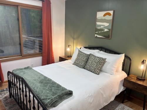 a bedroom with a white bed with pillows and a window at Wooded Nest, Cozy 3BR Chalet Near Spas, Downtown Berkeley Springs & Hiking in Berkeley Springs