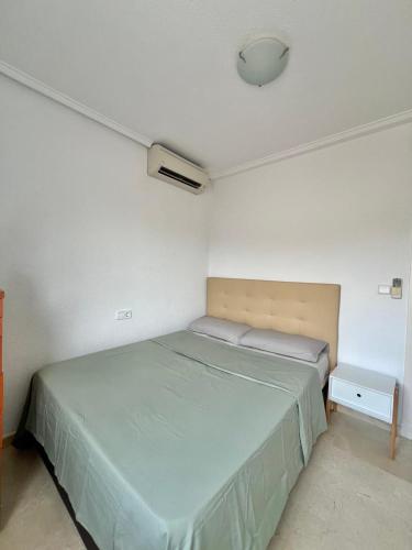 a bedroom with a green bed and a white wall at Roger's house frente al mar en Alicante in Gran Alacant