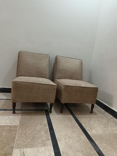 two chairs sitting next to each other in a room at RMT Residencia per room in Peshawar
