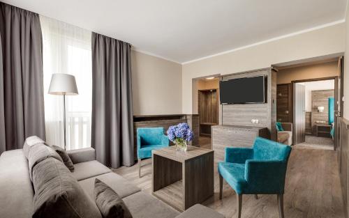 a living room with a couch and a tv at Hotel Konradówka Wellness & SPA - 300 metrów do centrum in Karpacz