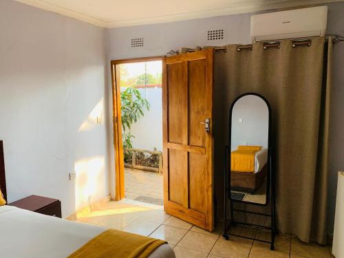 a bedroom with a door and a bed and a mirror at Plateau Guest House in Kasane