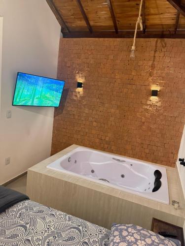 a bathroom with a tub with a tv on the wall at Riquezas de Lavras Novas - Chalé Safira in Lavras Novas