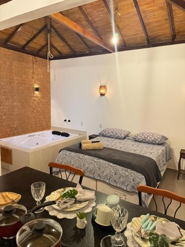 a room with a bed and a tub and a table at Riquezas de Lavras Novas - Chalé Safira in Lavras Novas