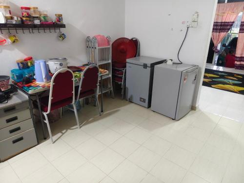a kitchen with two refrigerators and a table and chairs at Razeeya Homestay in Bachok
