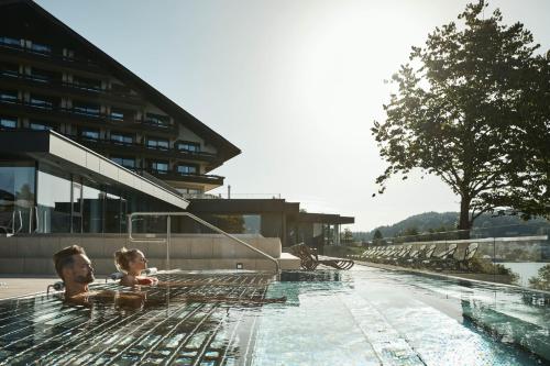 a man and a child are in a swimming pool at Hotel Karnerhof in Egg am Faaker See
