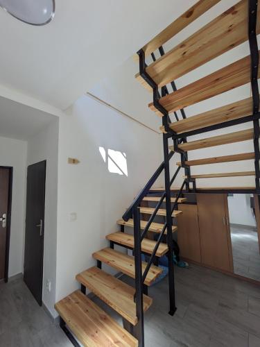 a wooden spiral staircase in a room with white walls at Apartmány U Lazara in Kutná Hora