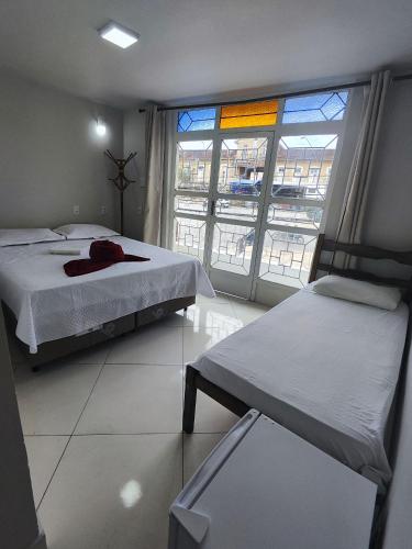 a bedroom with two beds and a large window at Hotel Estação in Diamantina