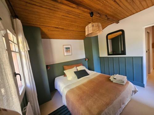 a bedroom with a bed and a wooden ceiling at Maison de charme au Canon in Lège-Cap-Ferret