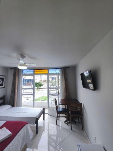 a bedroom with two beds and a desk and a window at Hotel Estação in Diamantina