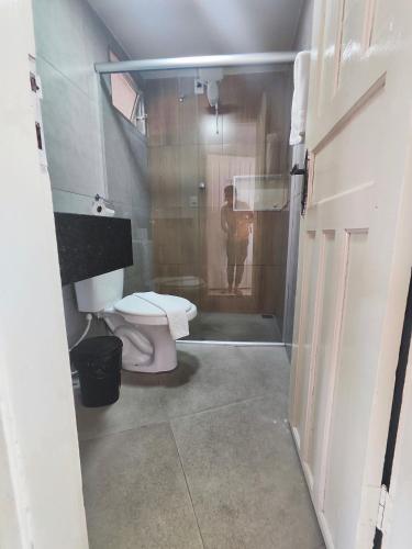 a man standing in a bathroom with a toilet at Hotel Estação in Diamantina