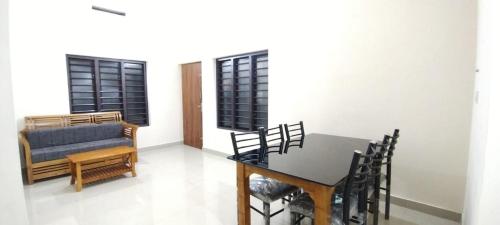 a dining room with a table and chairs and a couch at Eve's Residency in Meppādi