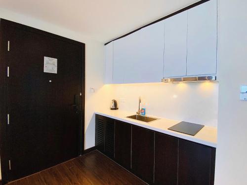 une cuisine avec un évier et une porte noire dans l'établissement The Sapphire Residence - AloTrip Homes, à Hạ Long