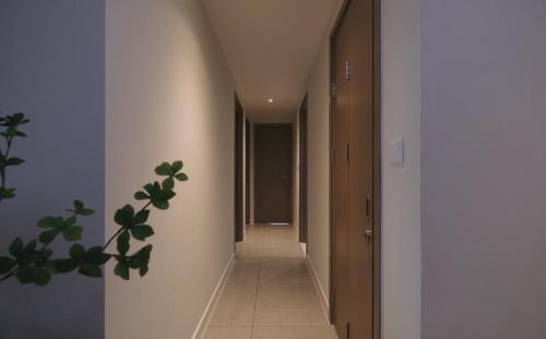 a hallway with a long corridor with white walls and a plant at Honey Wink - Zenity & D1 - Apartment in District 1 in Kon Rung (1)