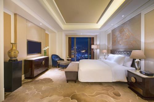 a bedroom with a large white bed and a large window at Wanda Vista Shenyang in Shenyang