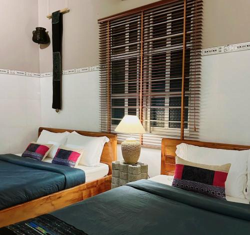 two beds in a room with a window at Chang's Hideaway homestay ConDao in Con Dao