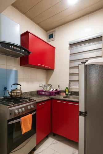 cocina con armarios rojos y fogones en Easyinn Shortlet Apartment, en Port Harcourt