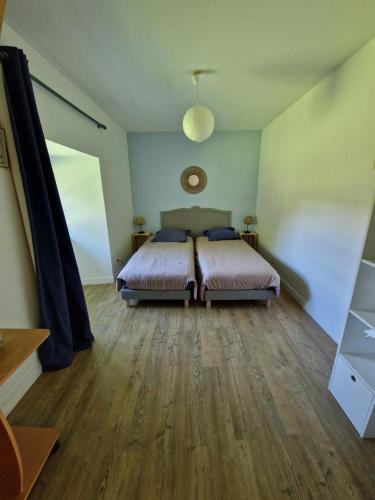 ein Schlafzimmer mit einem Bett und einem Holzboden in der Unterkunft Paimpont: Gîte de la Haute Fenderie in Paimpont