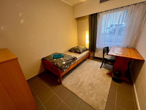 a small room with a bed and a desk and a window at Pension BettMan Erfurt in Erfurt