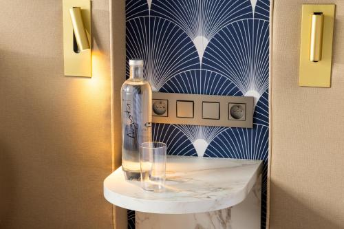 a bottle and a glass on a shelf in a room at Hotel The Augustin in Brussels