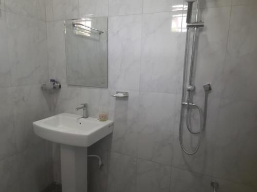 a white bathroom with a sink and a shower at Lodge in Resolute in Dambulla