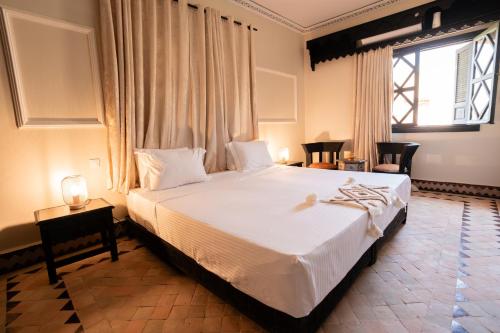 a bedroom with a large white bed and a window at Villa Marrakchia - Palais d'hôtes & spa in Marrakech