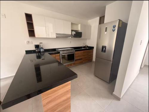 a kitchen with a stainless steel refrigerator and wooden cabinets at Acogedora casa en Capittala Leon-Facturamos in Santa Gertrudis