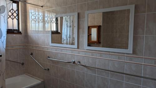 a bathroom with a sink and two mirrors at Capri24 - Modern apartment overlooking the sea in Amanzimtoti
