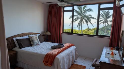 a bedroom with a bed with a view of the ocean at Capri24 - Modern apartment overlooking the sea in Amanzimtoti