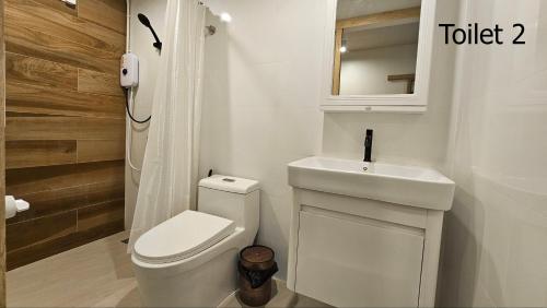 a white bathroom with a toilet and a sink at Tara Vela in Chumphon