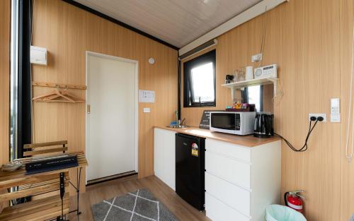a small kitchen with a microwave and a refrigerator at Bruce Farm Alpaca Cabin 2 by Tiny Away in Balclutha
