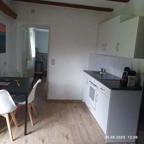 a kitchen with white cabinets and a table and a dining room at Landhaus Alpenblick in Obsteig