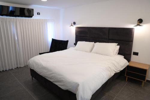 a bedroom with a large white bed with a black headboard at Puy Castele Hotel Tiberias in Tiberias