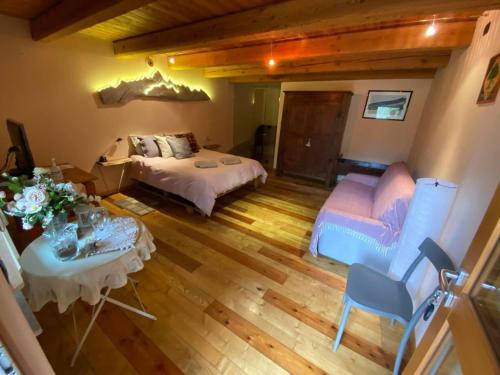 a bedroom with a bed and a table and chairs at L'Albero parlante- affittacamere del Bosco Incantato di Ostana con colazione inclusa in Ostana