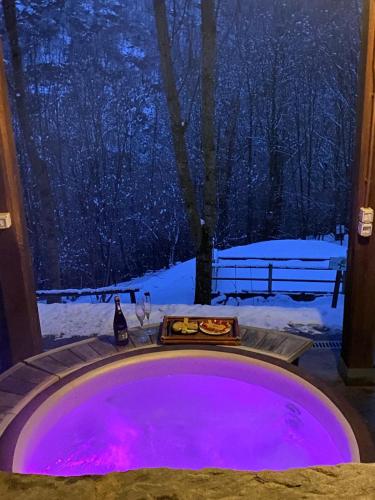 a jacuzzi tub with purple lights in the snow at L'Albero parlante- affittacamere del Bosco Incantato di Ostana con colazione inclusa in Ostana