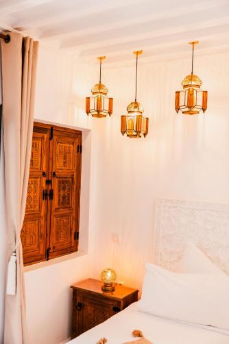 a bedroom with two chandeliers and a bed at Riad NL&S Collection in Marrakech