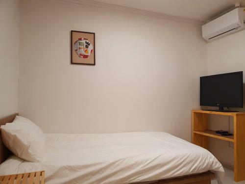Un dormitorio con una cama y un televisor de pantalla plana. en Stay Busan-gil, en Busan