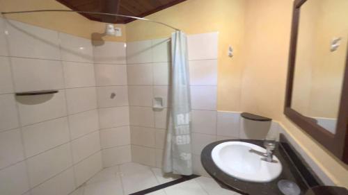 a bathroom with a shower and a sink and a toilet at Pousada Tassimirim in Ilha de Boipeba