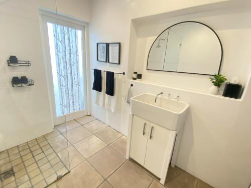a white bathroom with a sink and a mirror at Namaste Cottage - Garden Facing 2-sleeper Hideaway in Paternoster