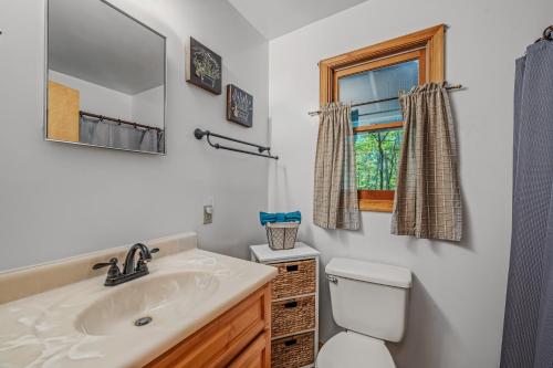 a bathroom with a sink and a toilet and a window at Cozy - Experience It All in Berkeley Springs