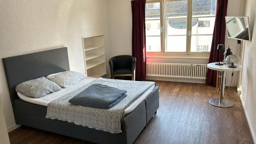 a bedroom with a bed and a chair and a window at 24Brugg City Stay in Brugg