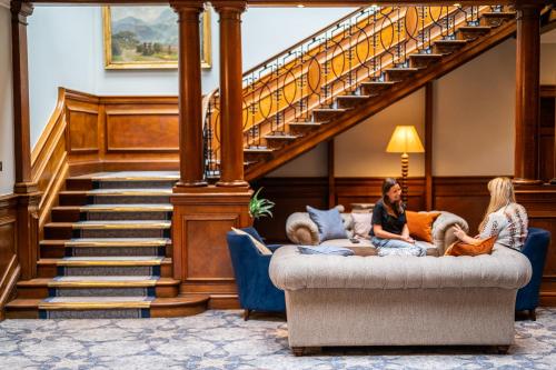 two women sitting on a couch in front of a staircase at Milton Hill House in Abingdon