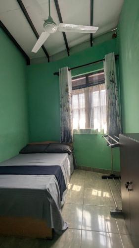 a green room with a bed and a window at Gishi's Happy Stay - Galle in Galle